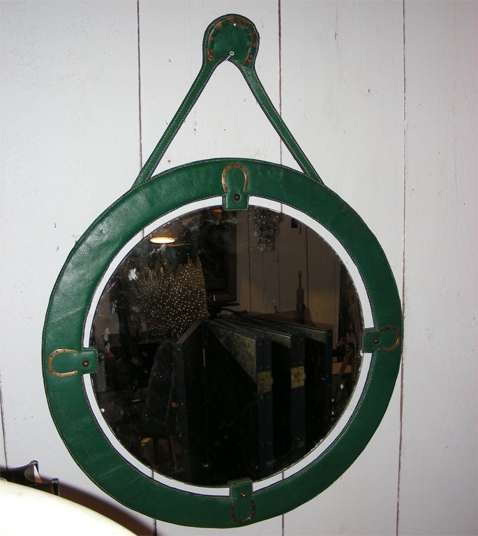 1950s round mirror framed in stitched green leather with gilt bronze horse-shoe motifs.
