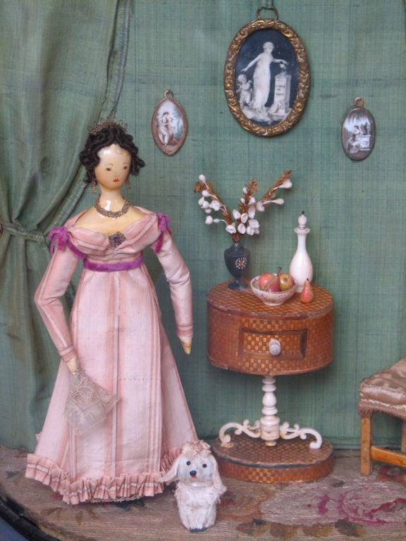A vitrine depicting a doll house interior utilizing antique fabric and doll house furnishings, including a straw work marquetry table. Signed and dated, H. Bruce fecit, 1953, Entitled, 