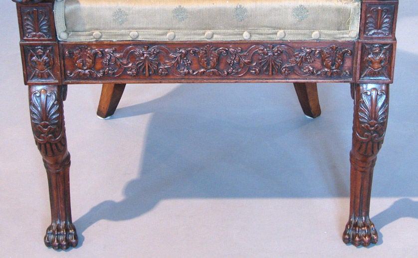 A rare early 19th century neapolitan armchair executed in mahogany and mahogany veneer, the back splat and blocks over the animal form front legs carved with trophy motifs, the arm posts in the form of swans astride cornucopia, circa 1815.