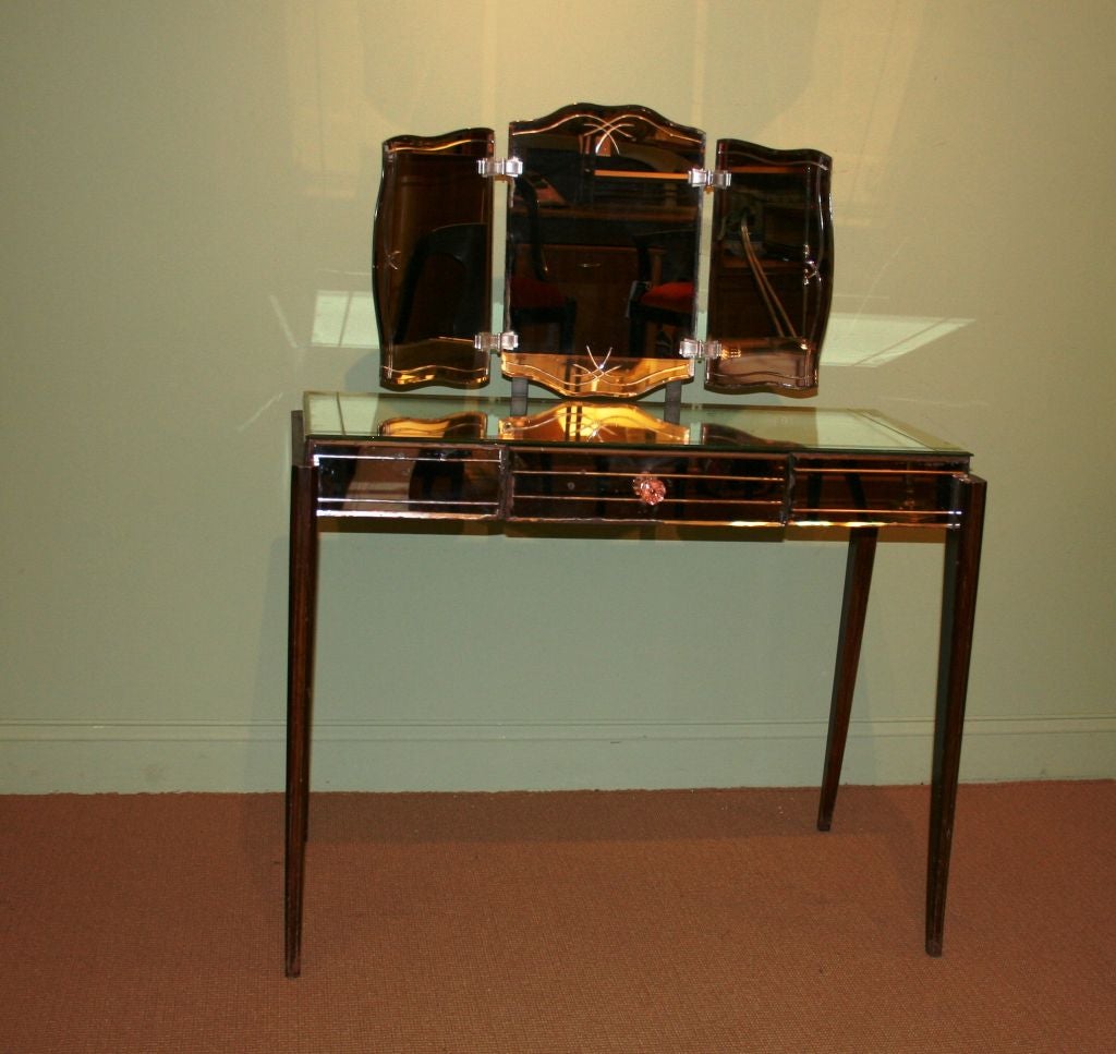 Elegant mirrored vanity with etched and beveled mirrored panels on the top and side with beautifully etched and beveled tri-fold mirror.  Unusual rose colored glass pull.