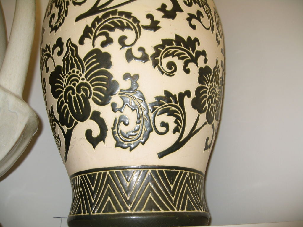Eine stark verzierte Vase aus Terrakotta. Der Grund ist ein cremefarbenes Biskuit-Finish und das Muster ist eine erhabene sehr dunkelgrüne Glasur.