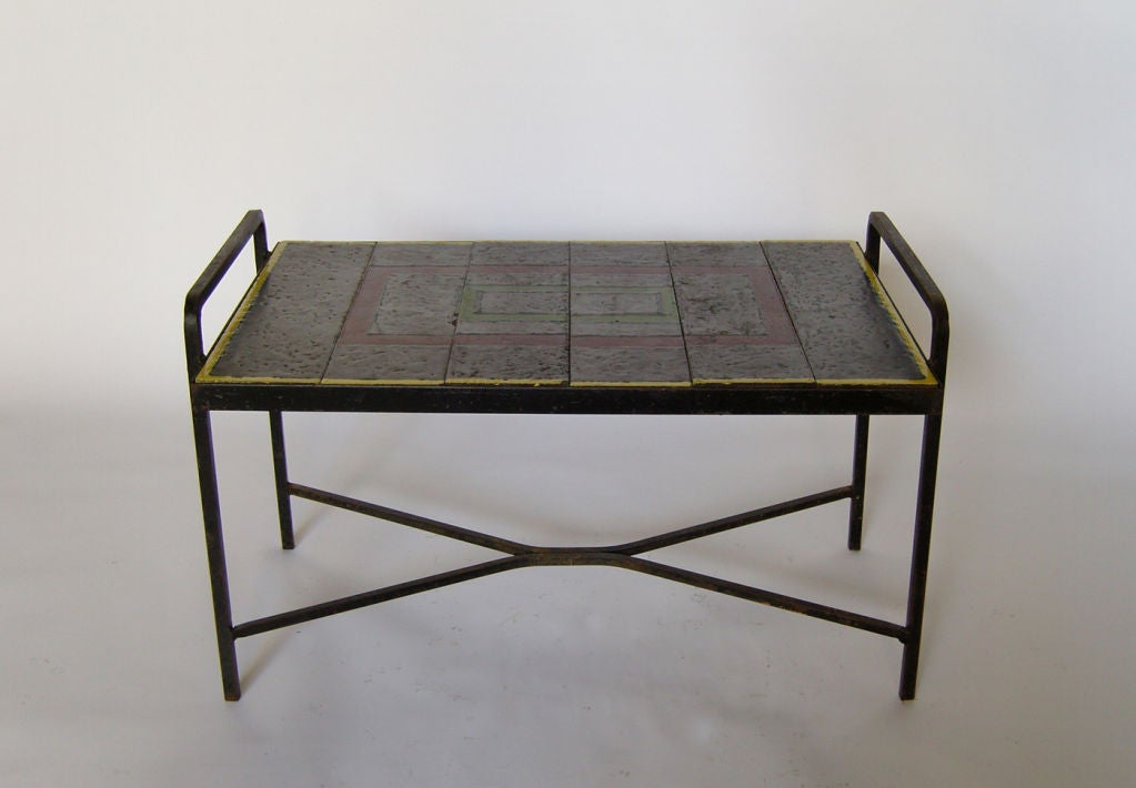 Mid-Century, with a wrought Iron base that supports an enameled lava tiles top. 
