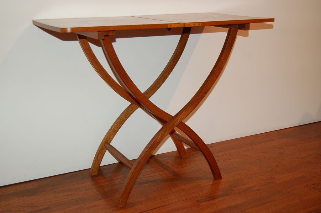 Folding table in mahogany on a curved X base.