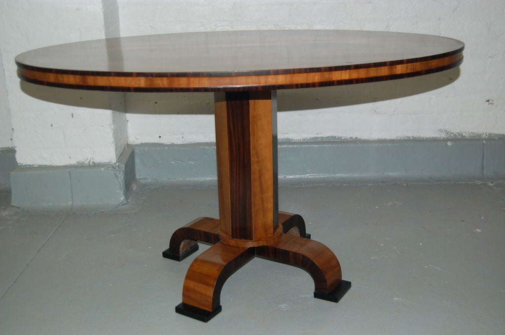 A 1930's Swedish Deco occasional table with oval top in bookmatched birch veneer and faceted pedestal base with feet, contrasting in Macassar ebony.