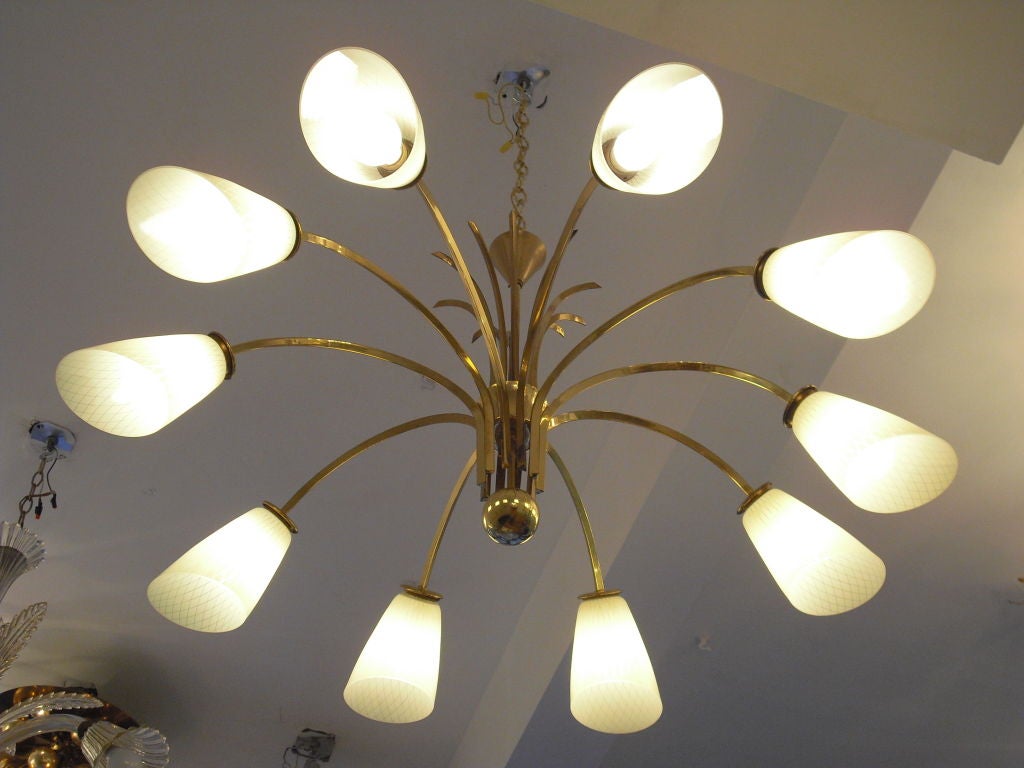 A large ten light brass fixture with glass shades by famed Austrian lighting maker, Kalmar. The custard glass shades have a decorative diamond pattern. The chandelier can be flush to the ceiling or dropped on a longer pole or chain.