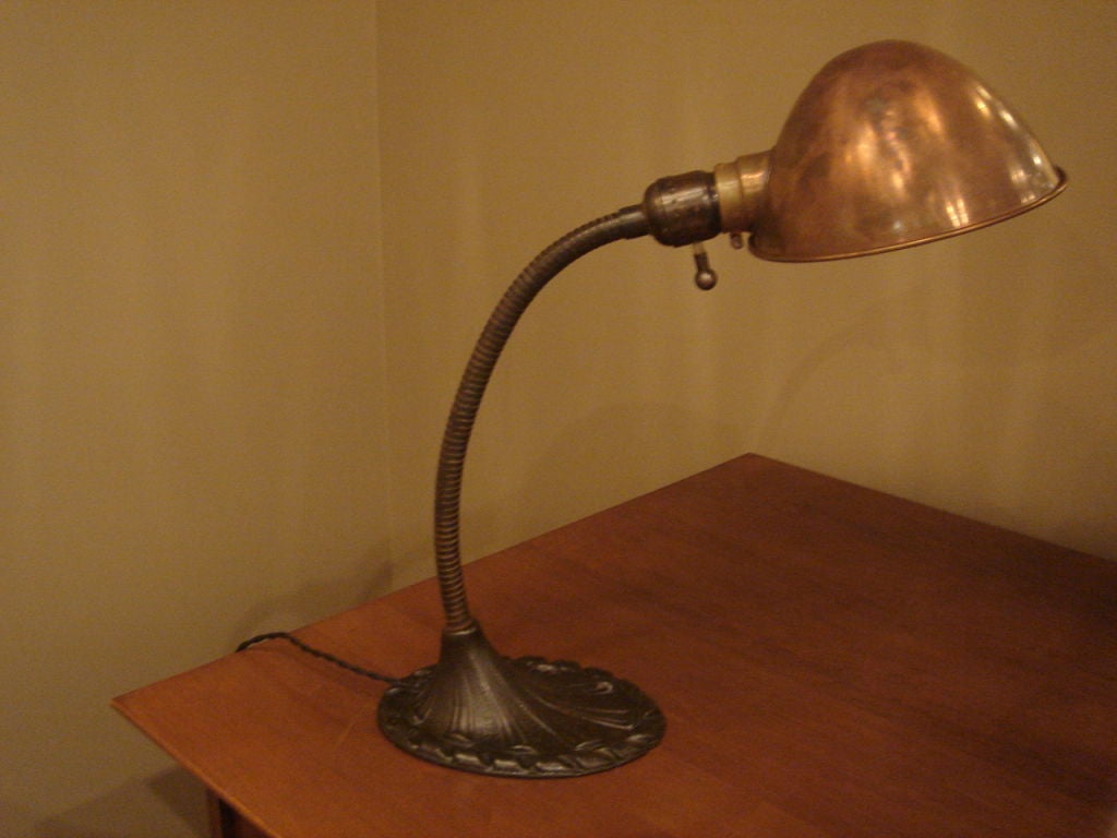 Antique industrial-style desk lamp made by the Aladdin Mfg. Company.  USA, circa 1910.  Features adjustable gooseneck with period-designed base and twist on-off switch.  All original.  Patinated brass (black finish) base and arm with copper shade. 