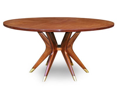 A LIVELY ITALIAN 1950'S SOLID MAHOGANY CIRCULAR BOOMERANG CENTER TABLE WITH SIX SUPPORTS AND BRASS SABOTS. The six slender boomerang-form chevron supports with sleek brass sabots; joined at each apex to the central circular disc; and raising the