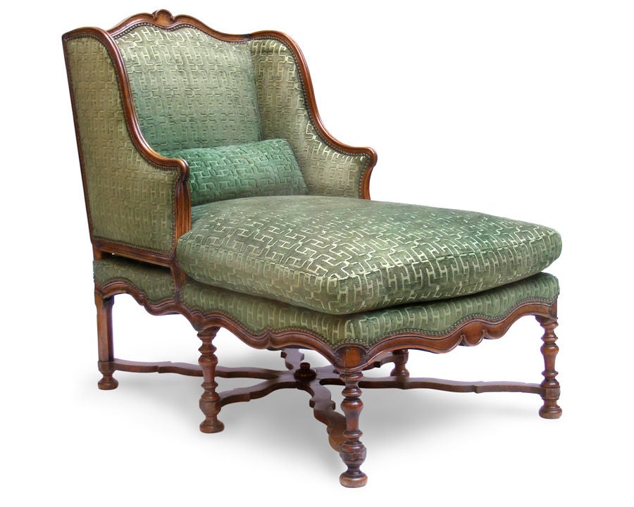 A QUIXOTIC FRENCH BAROQUE STYLE WALNUT LOUNGE WITH A WINGED BACK AND LATER GREEN CUT-VELVET UPHOLSTERY. The rectiform lounge; with the serpentine crest rail flanked by waterfall wings; emanating the rectangular bed above the serpentine rail; all