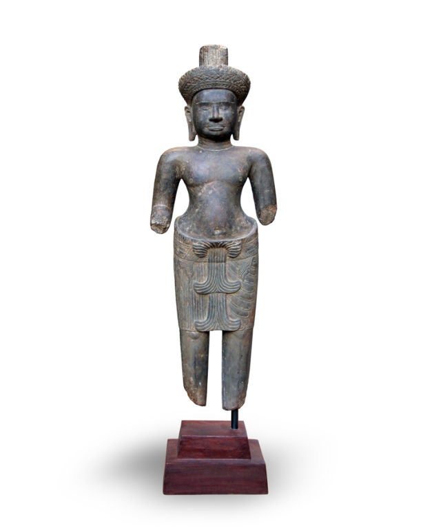 A SUBLIME KHMER (CAMBODIAN) CARVED STONE BRAHMANIC STANDING DIETY. The male figure in hieratic standing pose; clad in a jeweled belt over a pleated sampot with a double fish-tail flap to the front; with a ribbed choker; the serence countenance