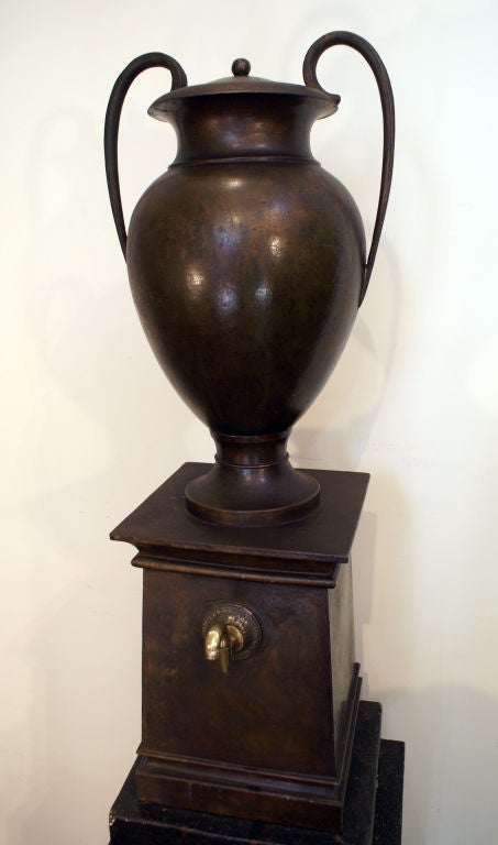 A rare early 19th century tole painted faux bronze water urn on original faux painted marble wooden stand. Made in France, circa 1800. From a noted dealer, decorator.
