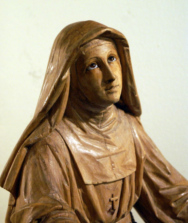 A well carved figure of a praying nun with glass eyes made in Central Europe during the 19th century. Probably painted and gilt with traces of gesso remaining.

  