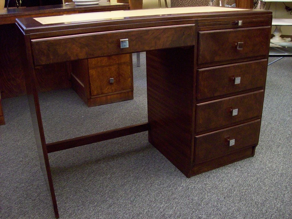 A smaller sized mid-century desk from England. The wood grain of this desk is  notable, with walnut burl veneer top and front and horizontal macassar veneer on the sides.  New leather top and new French chrome handles. Very chic. Five drawers with a