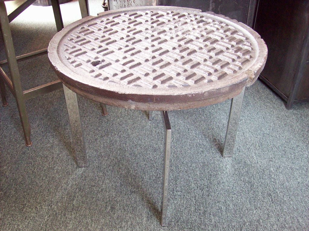 Vintage New York City Department of Public Works iron manhole cover handcrafted into a table. This cover is the real thing and is quite heavy! Set on a modern shiny chrome base (see image 2), it makes quite a unique end table. Reduced.  NT