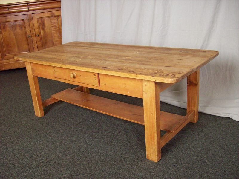 An antique coffee table from Ireland. Made of a honey colored pine, this good sized coffee table has one drawer and a lower shelf for books.