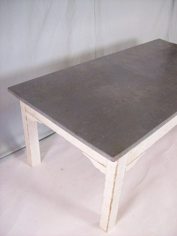 An antique coffee table from France. The zinc top is richly patinated. The white paint of the base has an appropriate amount of distress for its age. Reduced from $2400. NT