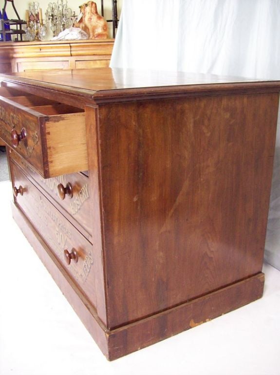 An antique set of drawers from England. The mahogany has a warm color and patina, but is damaged to the top and needs to be restored. (Some veneer missing, could just be sanded and stained/waxed.) Writing on the three drawers was recently painted,