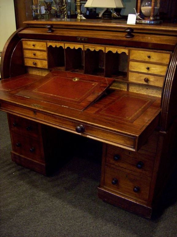 A spectacular antique two part cylinder desk from England. The color and patina of the mahogany are exceptional. The leather has been replaced. Note the six small interior drawers and wonderful apron on the cubbies. This is just a very well made