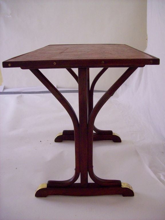 A Thonet bistro table from France. This rectangular base is bentwood with terrific brass accents-base feet and center rail. The top, recently added, in crackled deep red color, is much like the original. Size lends itself to many uses, obviously as