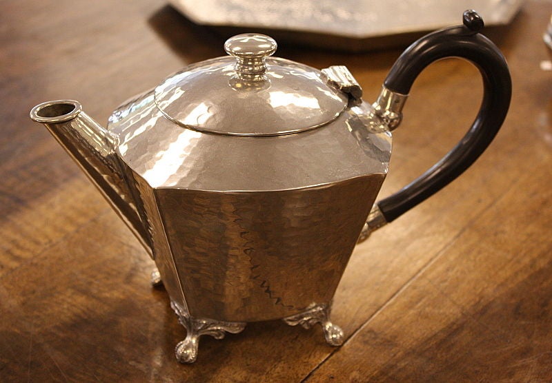 A small hand-hammered pewter tea set from England, circa 1930.  The tea pot, sugar bowl and creamer all have diminutive claw feet.  The tea pot has stylized black handles, probably bakelite.  The height measurement is for the tea pot, which is the