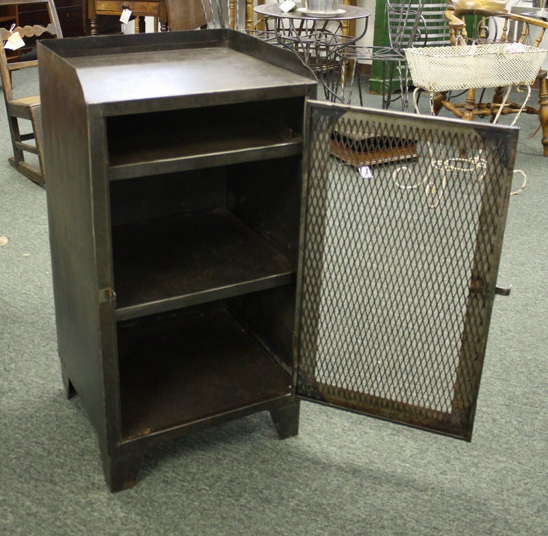 A nice mid-size turn-of-the-century French Industrial steel cupboard with one door and two interior shelves. The mesh door and swing latch closure give this piece rustic appeal. Height measurement includes the galleried back. This could be a bedside