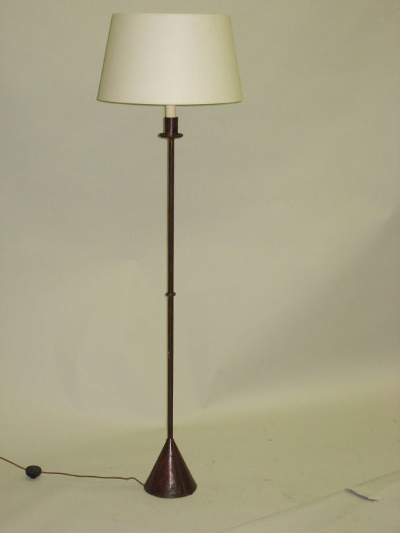 A sober Mid-Century floor lamp with a cone-shaped base supporting a single stem with a ring in the center, the entire lamp covered in brown hand-sewn leather. Shade is for demonstration purposes only.
