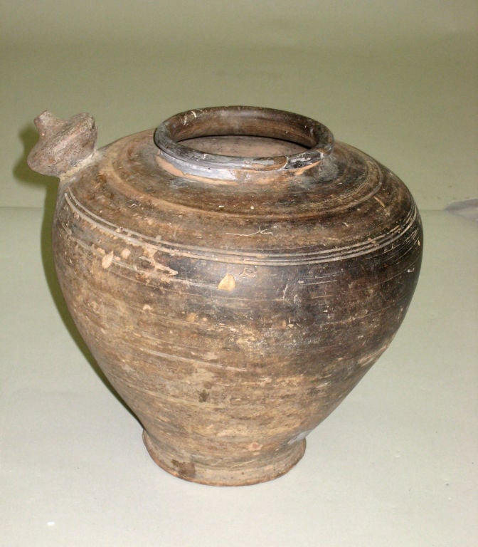 An ancient terra cotta pottery vessel / urn / vase / pitcher from the Khmer region of South East Asia. 

A sober form that provides a complement to a Mid-Century or modern environment.

