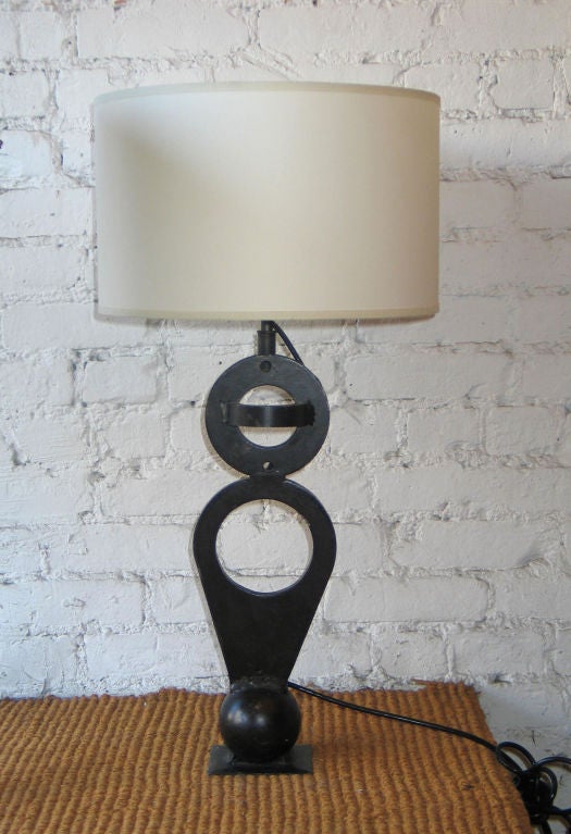 Coppia di lampade da tavolo francesi della metà del secolo scorso in ferro battuto a mano a forma di sculture geometriche moderne che utilizzano le forme di una palla e di cerchi.

Siglata con le iniziali dell'artista sul retro.