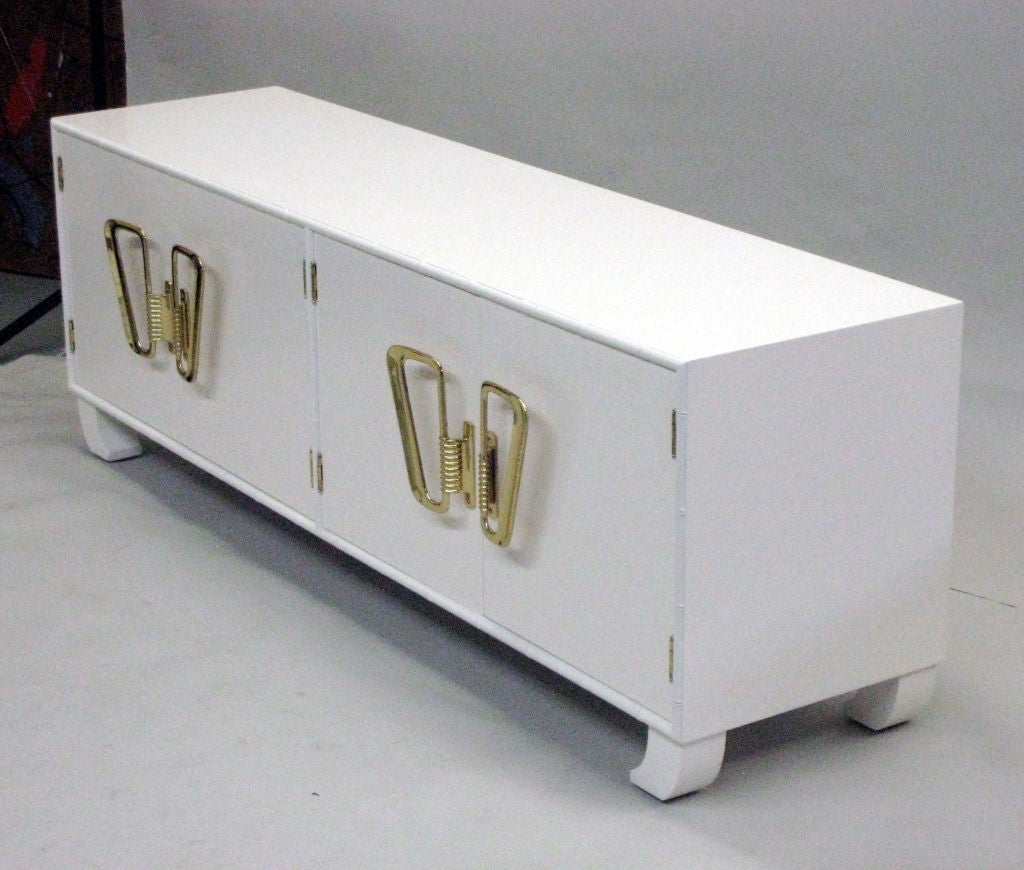 Italian Mid-Century Modern or Hollywood Regency style white lacquered cabinet, sideboard, chest, commode, credenza, étagère or shelves with exotic inward turned legs and faux bamboo frame.

Stunning Italian solid brass door hardware completes the