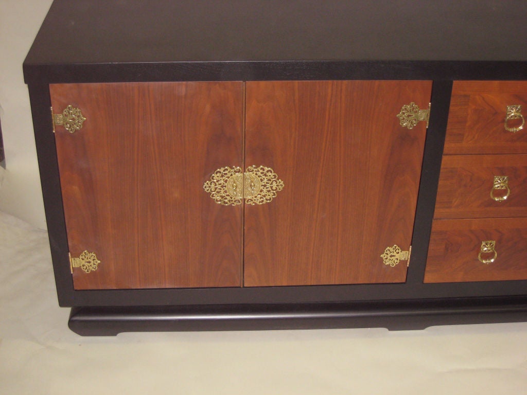 Large Italian Mid-Century Modern cabinet, sideboard, credenza, dresser, chest of drawers or commode set on a modified plinth base featuring a contrast between ebonized and light woods and elegant brass hardware. 

A high quality piece with a lot