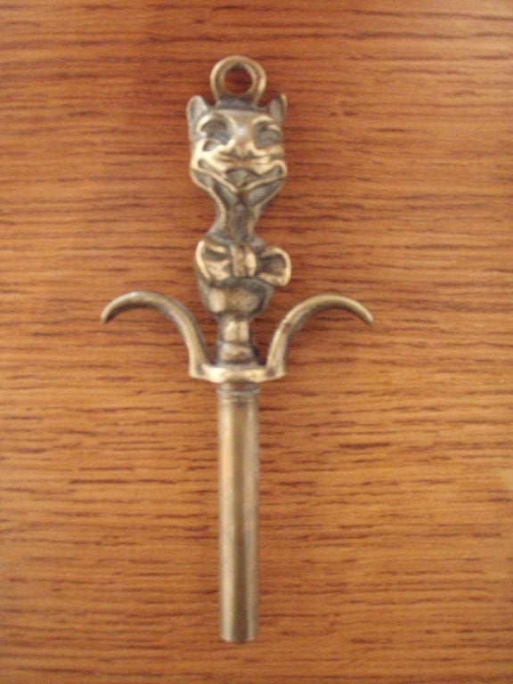Brass cheshire cat has a smiling face and bowtie.  Curved finger grips and brass screw cap.