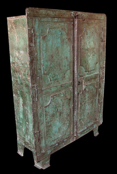 A bold and well-patinated French industrial 2-door blue-green painted iron cabinet; the rectangular cabinet fitted with 2 paneled door fitted with robust hinges and assembled with large-scaled rivets; raised on short splayed legs; the interior