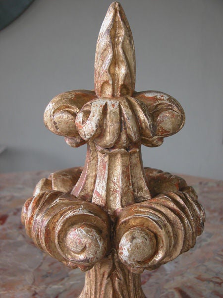 An exuberantly carved English neo-gothic giltwood finial; the graduated spire of gothic inspiration with 2 tiers of scrolling volutes resting on a circular plinth; all over a later square plinth