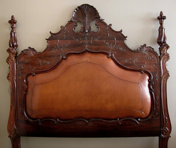 A rare and exceptional Portuguese Colonial carved rosewood bed with head and foot board; the pierced cartouche crest with robust shell carving flanked by curvaceous stiles with spiraling finials; the foot board with similar stiles