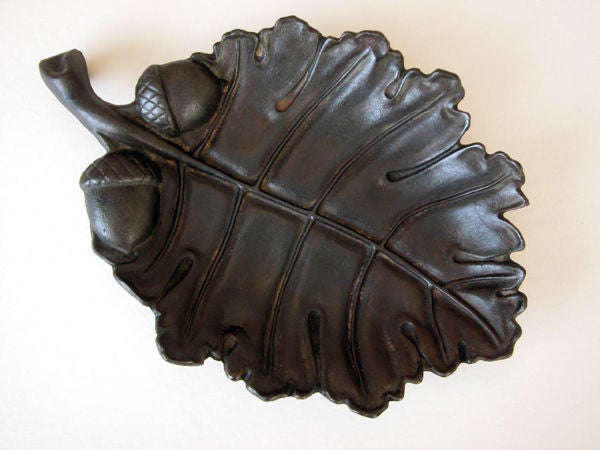 A boldly-scaled American arts & crafts cast iron oak leaf bowl; the well-rendered leaf with thick stem flanked by 2 acorns; with a central vein emanating to the scalloped edge