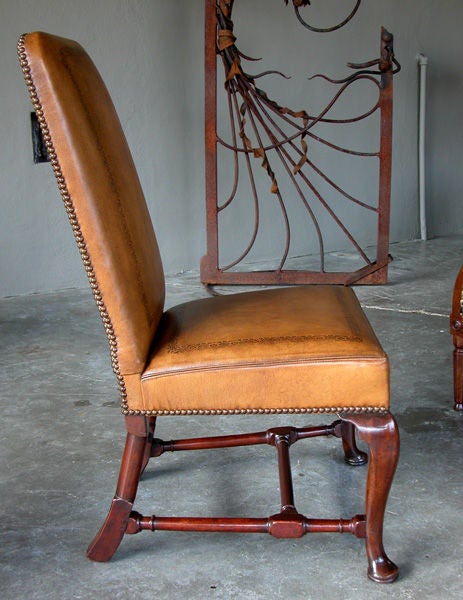 A handsome English Queen Anne walnut side chair with embossed leather upholstery; the tall rectangular upholstered back above a square tight seat; raised on cabriole supports with splayed legs at the rear; all joined by an h-stretcher