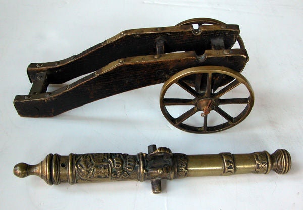A well-crafted and detailed pair of Dutch brass replicas of 17th century cannons; each solid brass cannon adorned with a well-detailed crest; resting on wooden carriage with brass spoked wheels