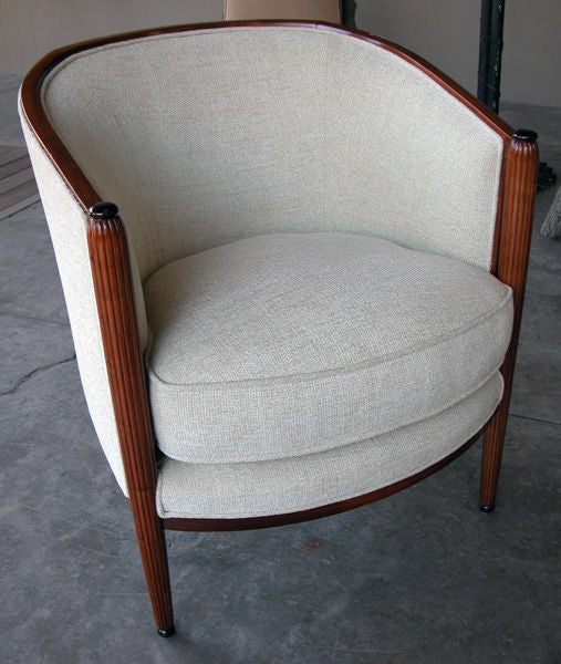 A stylish set of four French art deco walnut club chairs; each with incurved sloping crest rail above a padded back over a bowed loose seat cushion; flanked by gracefully tapering reeded suports ending in a compressed spheroid foot