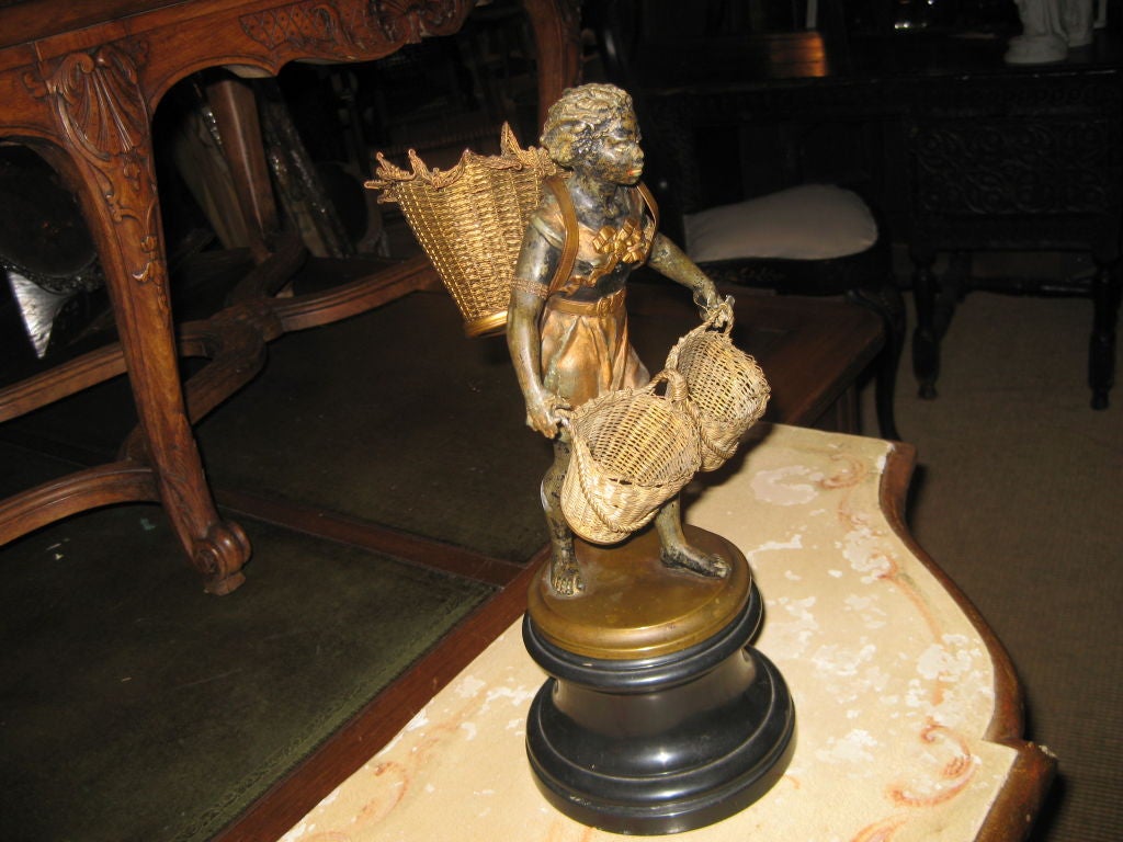 Charming nubian figure with ebonized wood base and the figure is cold painted white metal, bronze, and brass wire.