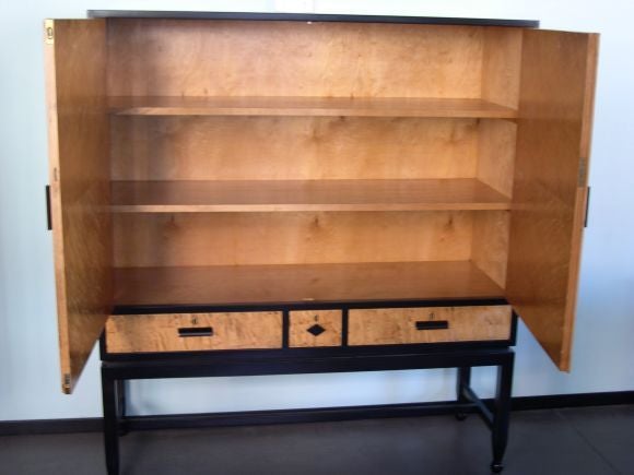 Swedish art deco cabinet in golden flame birch with ebonized birch casing and base. Made in Sweden ca. 1930's. This piece could easily serve as an entertainment cabinet as there is no center divider.