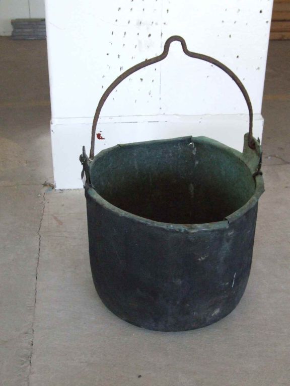 An 19th century English copper boiler with rolled rim and iron lifting handle on raised mounts, the bucket with much wear and tear  and surface patination