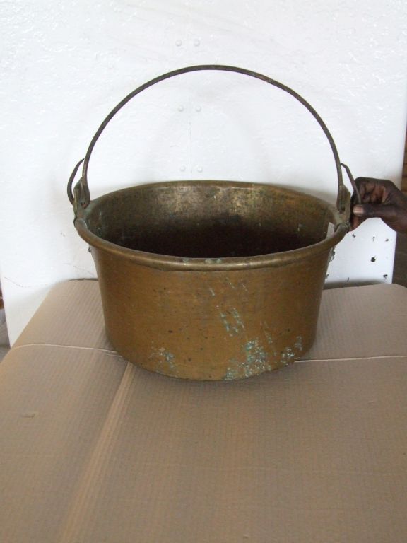 An 18th century English brass cauldron having flared mouth with rolled rim, substantial handle supports and wrought iron carrying handle.  Useful now as log bin next to a fireplace.

firewood, kindling, log holder