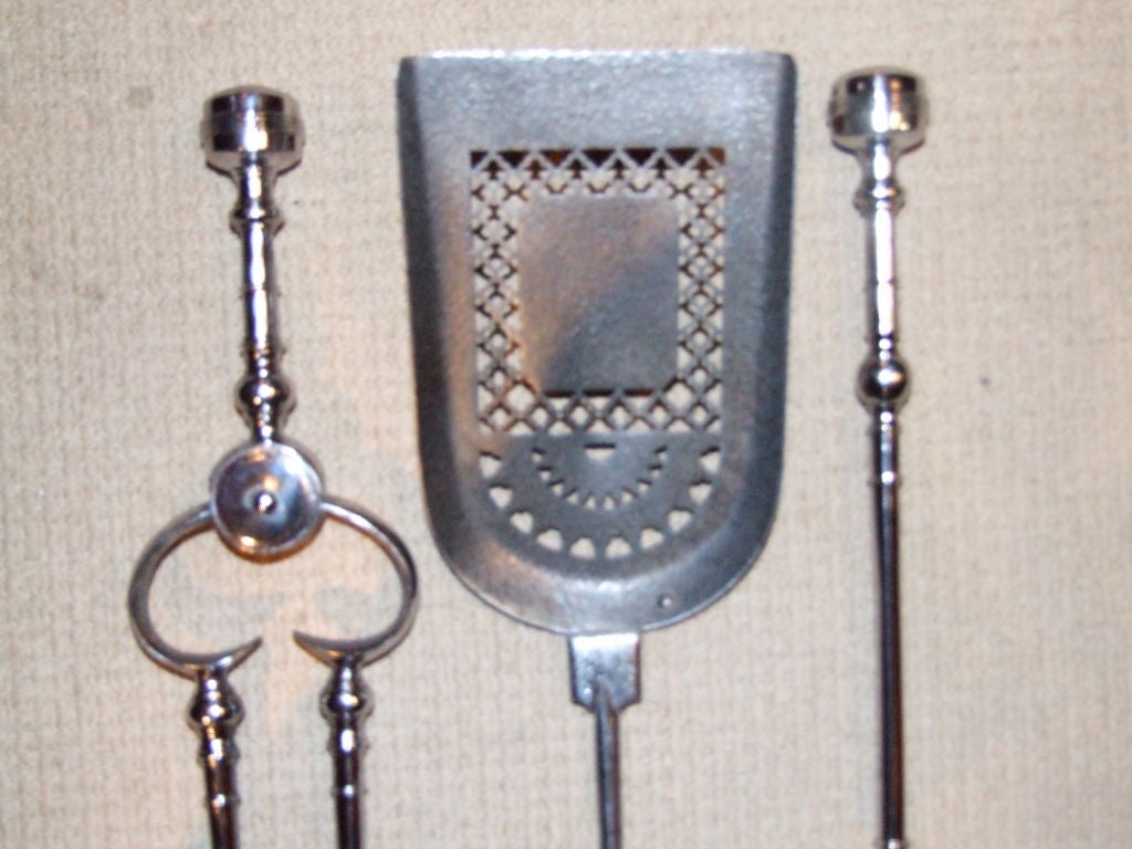 A fine set of three Regency period English firetools comprising poker, tongs and shovel, in gunmetal steel with large button finials and intricate piercework cut outs on shaped shovel bowl.