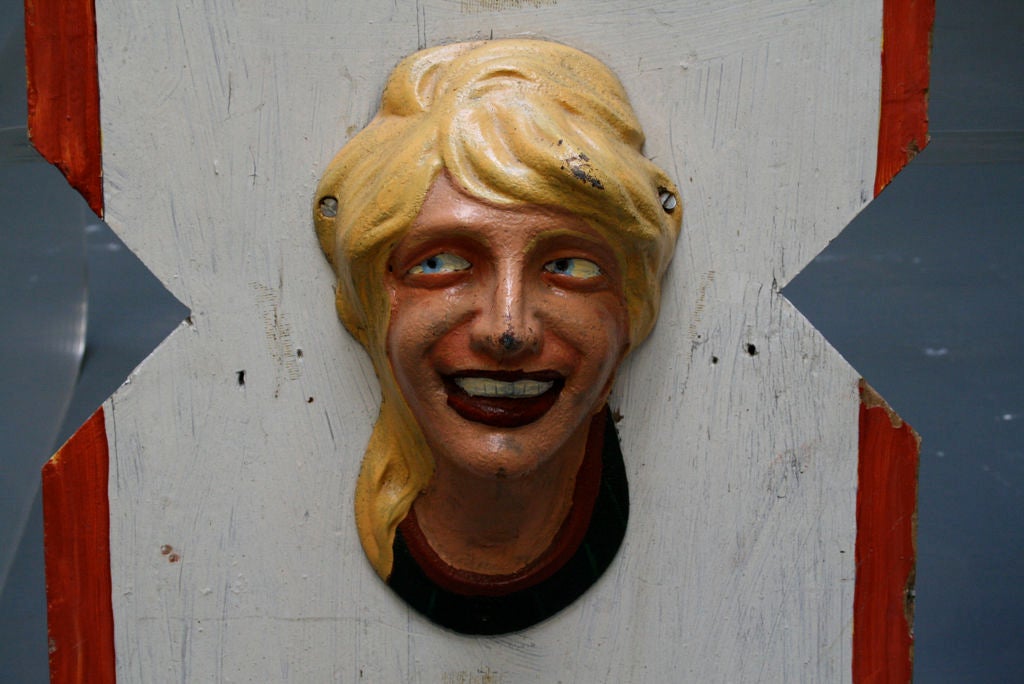 Ripped from the heart of a demolished early 20th century merry-go-round, these Americana plates (there is a specific name for these that I used to know) covered the motor mechanism. Features grinning cross-eyed blonde lass of cast metal fastened to