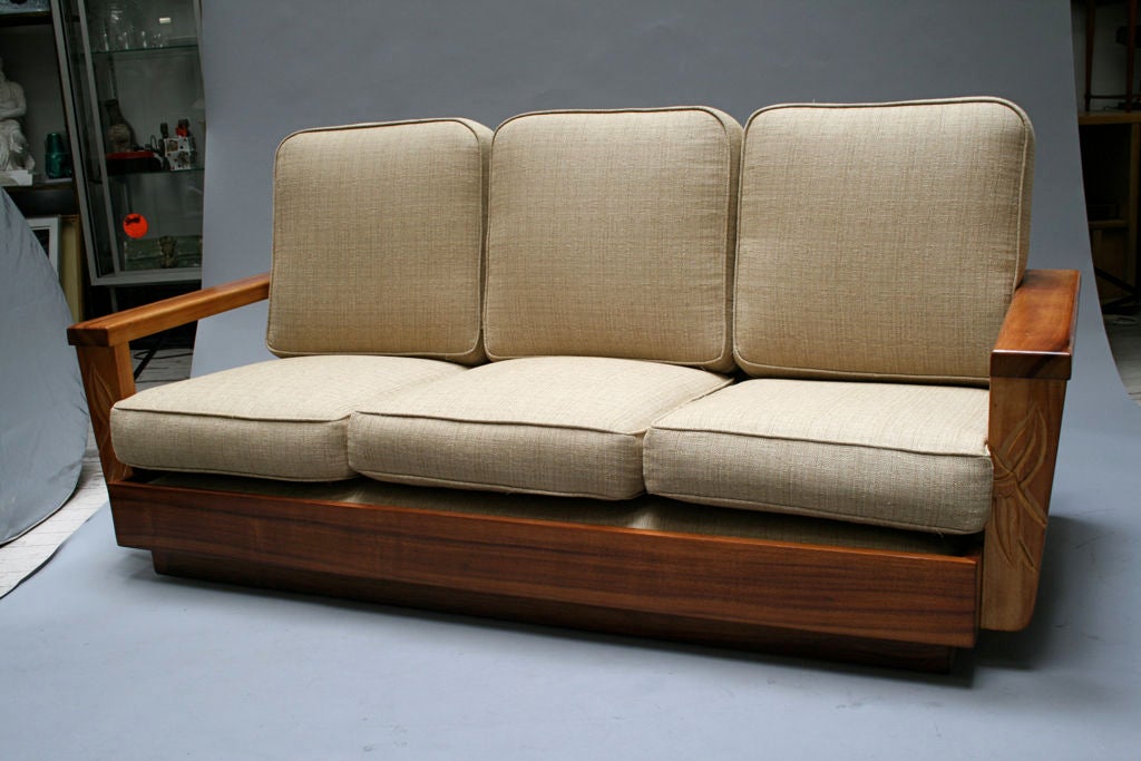 Made by Hawaiian convicts as part of a job traing program in the 1940's and 1950's from solid koa wood planks (now protected). Features native foliage hand carved on front arms. Re-upholstered with fabric ressembling grass-cloth and new spring