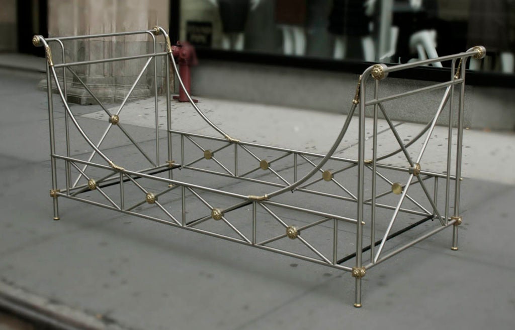 Campaign Style Daybed by Paul M. Jones, inspired by the designs of Maison Jansen, USA, circa 1965. Neoclassical inspired daybed in brushed steel with bronze details.  The bed has large curule-forms at the head and base and four small curule-forms on