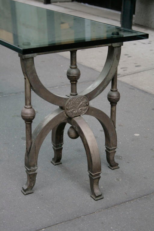 Each elegant base of silvered-bronze with arched swivel legs and delicate foliate design support a beveled-edge 3/4" glass slab top. Silver is patinated but can be buffed to a brighter finish if desired.