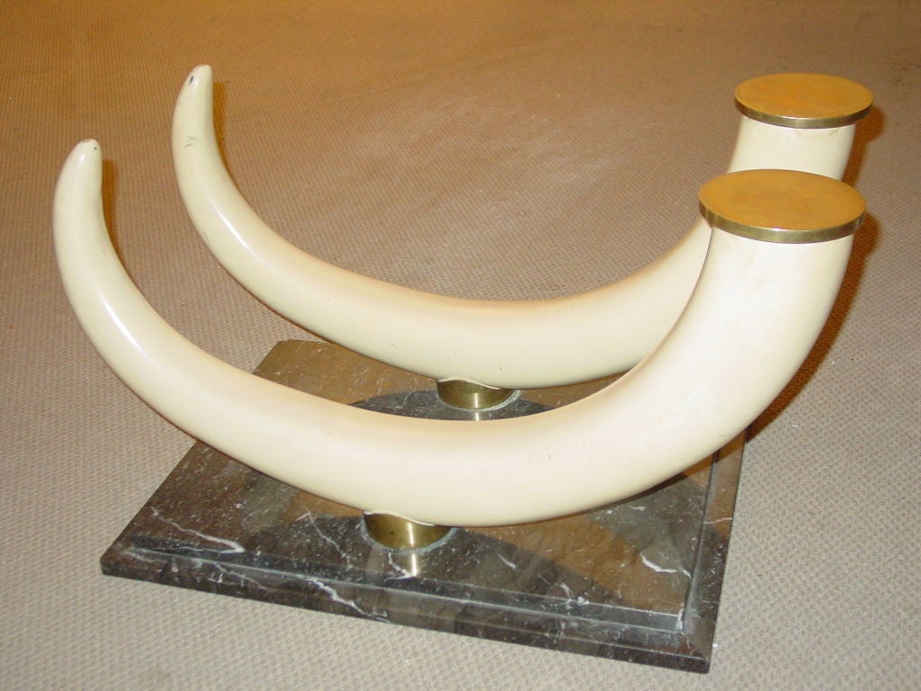 the bevelled rectangular glass above twin tusk form supports on a stepped grey and white veined marble plinth