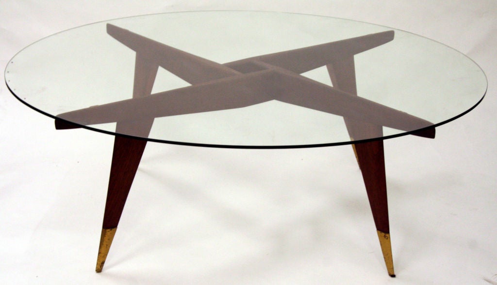 A rare example of a cocktail table by Gio Ponti  for Singer and Sons. Hand shaped walnut frame bearing few right angles and a sharp razor edge taper, terminating with brass sabots. Complete with original tempered glass top bearing five dimples.