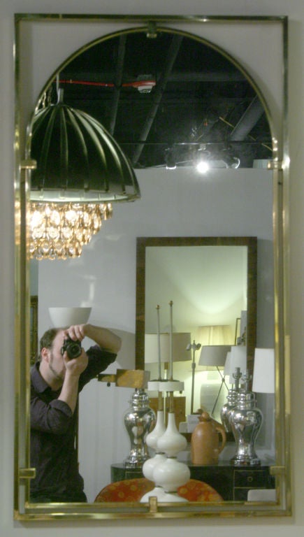 A reductive arch form mirror surrounded by a rectangular brass-plated steel frame by John Stuart. American, circa 1960.