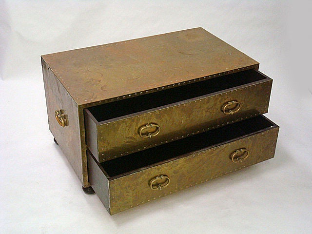 A  brass clad two drawer commode with elaborate copper studded surface, solid brass handles and wood bun feet. Spanish, circa 1970.